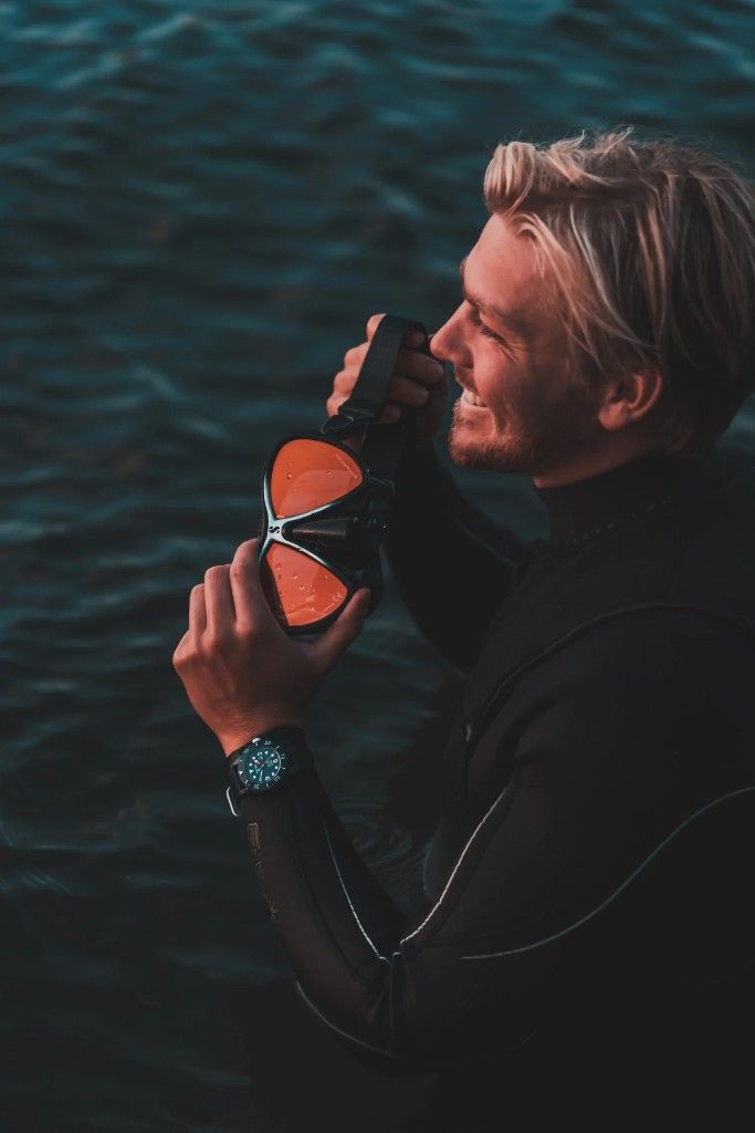 David Wendel Thoms holding a diving mask with orange lenses.
