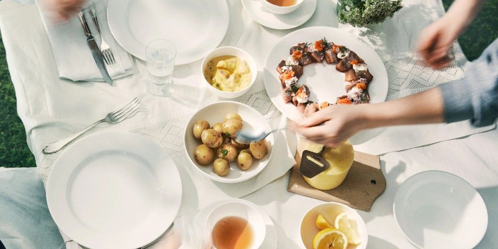 Swedish summer table with porcelain, new potatoes, herring, and cheese.
